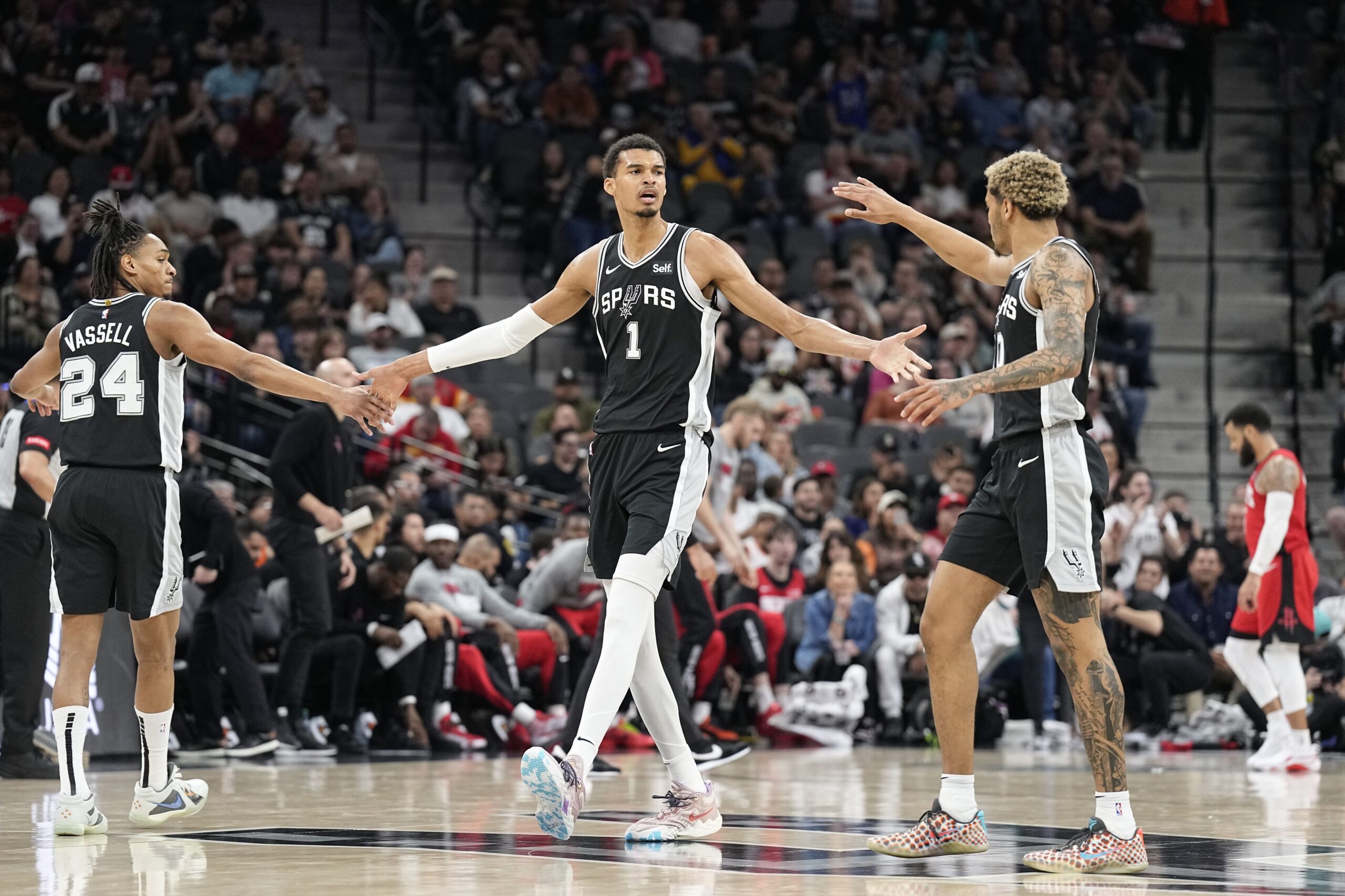 Mar 12, 2024; San Antonio, Texas, USA; San Antonio Spurs forward Victor Wembanyama (1) reacts with guard Devin Vassell (24) and forward Jeremy Sochan (10) before a time out during the first half against the Houston Rockets at Frost Bank Center. Mandatory Credit: Scott Wachter-USA TODAY Sports