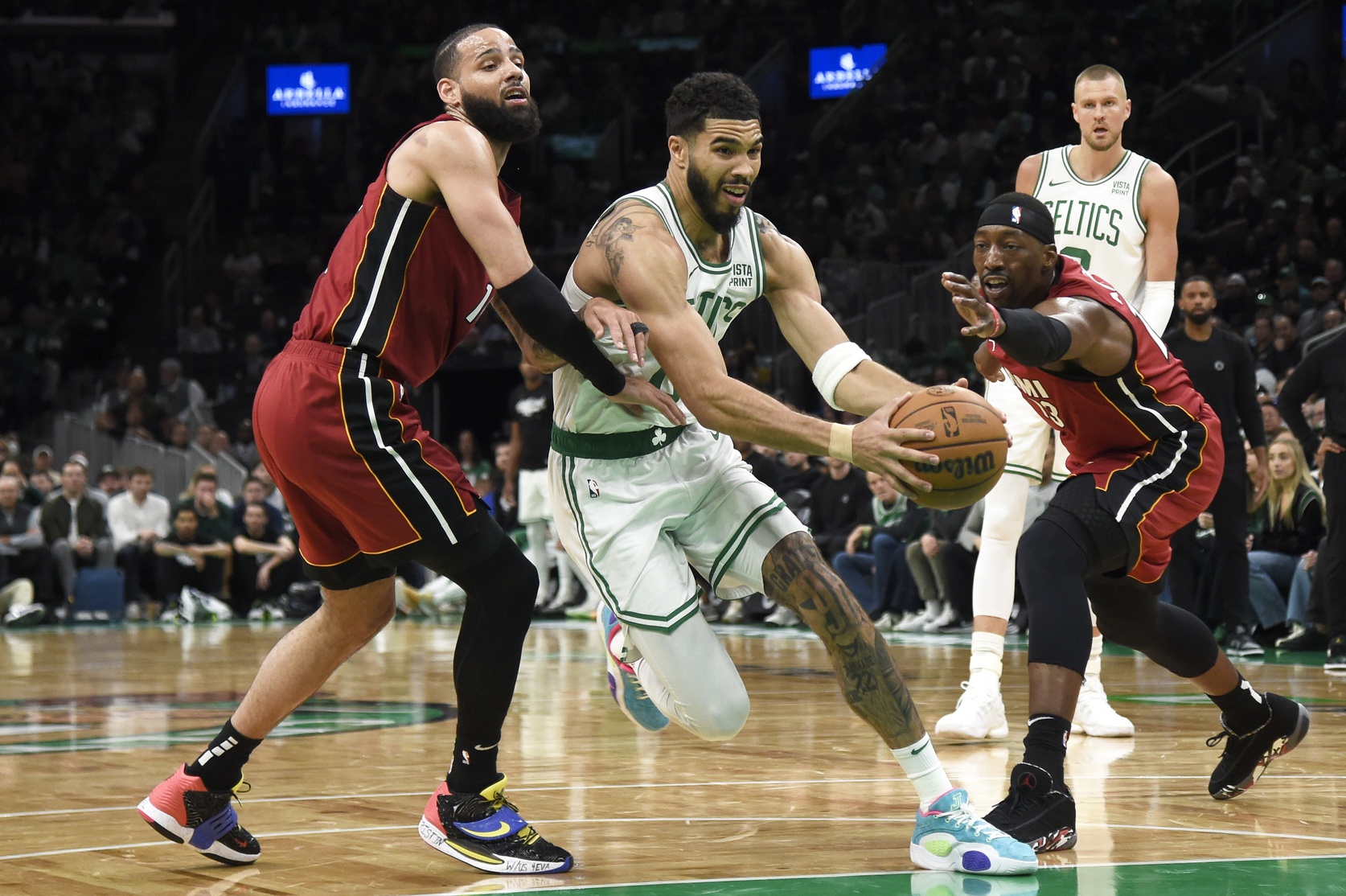 Apr 21, 2024; Boston, Massachusetts, USA; Boston Celtics forward Jayson Tatum (0) drives to the basket between Miami Heat forward Caleb Martin (16) and center Bam Adebayo (13) during the second half in game one of the first round for the 2024 NBA playoffs at TD Garden. Mandatory Credit: Bob DeChiara-USA TODAY Sports